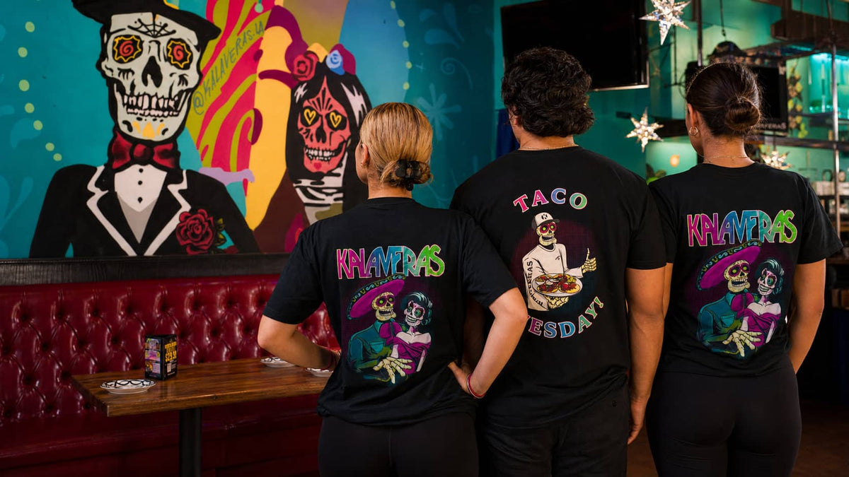 Three models wearing Kalaveras Couple and Taco Tuesday shirts at the Bellflower restaurant