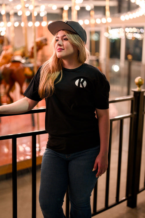 Woman wearing the black Kalaveras Heritage Los Novios Graphic Tee, front view at a Kalaveras restaurant
