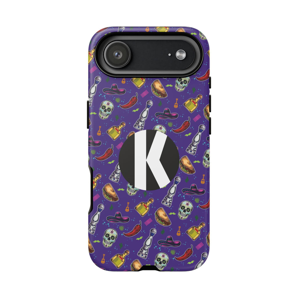 A purple phone case with a Halloween-themed pattern of skulls, chili peppers, bottles, and hats, featuring a large black circle with a white letter 'K' on the back.