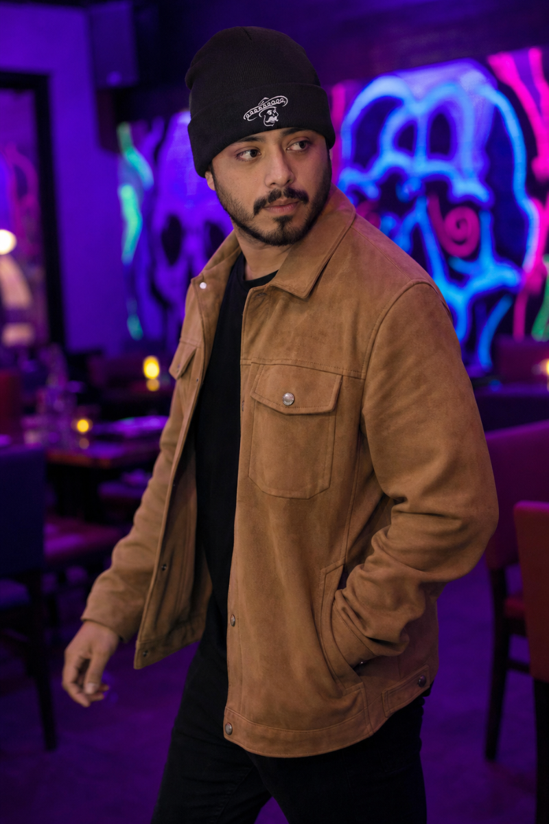 Man wearing black Kalaveras embroidered beanie in front of a neon skull mural